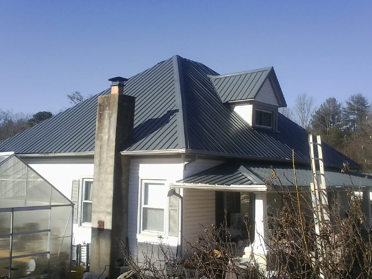 Dark blue standing seam metal roof on a white farmhouse with dormer — Slate & Tile Roof Repair by Roofing Brothers in Weehawken