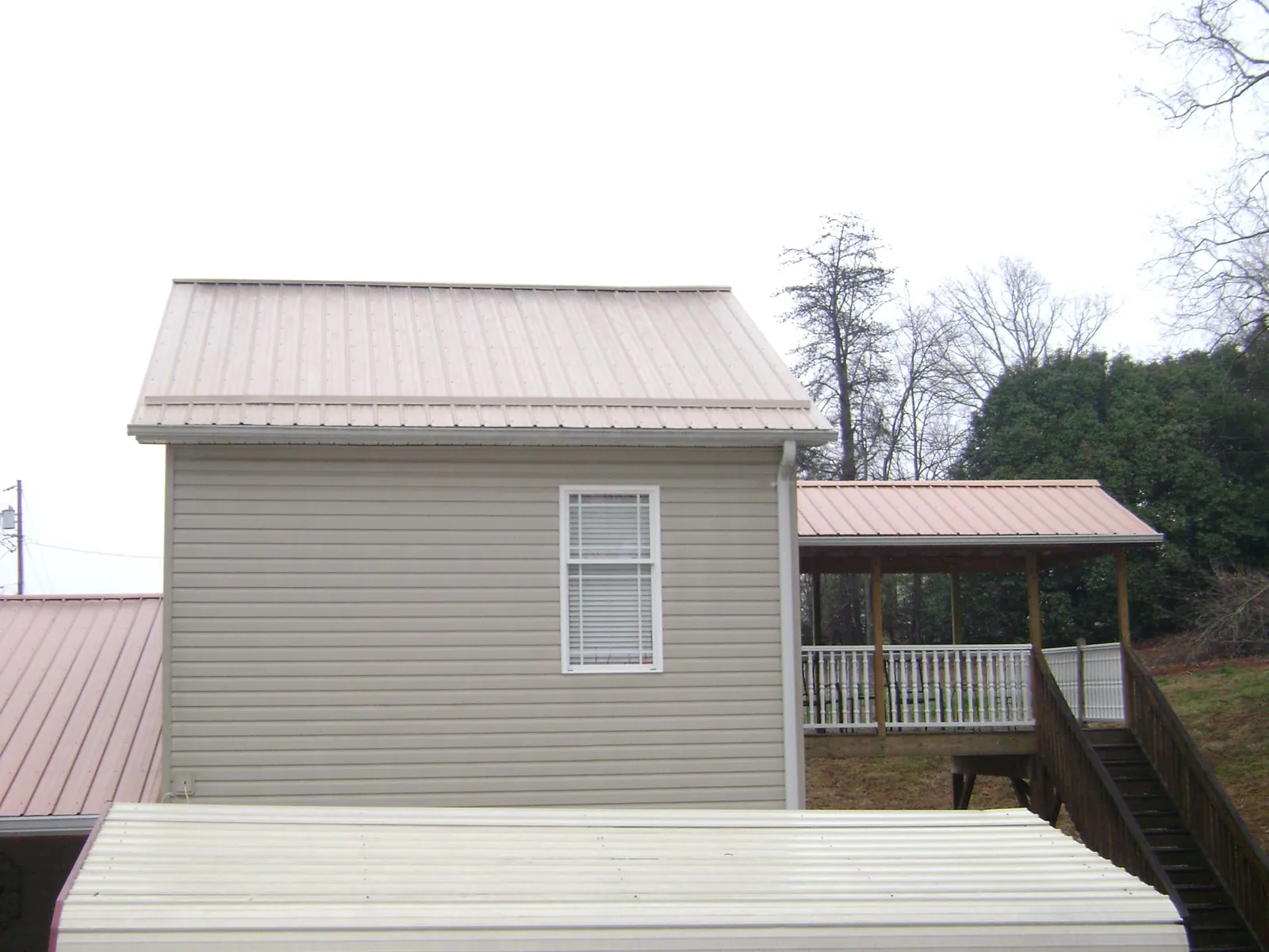 Tan metal roofs on a two story addition and attached porch, from a Roof Replacement job in Weehawken