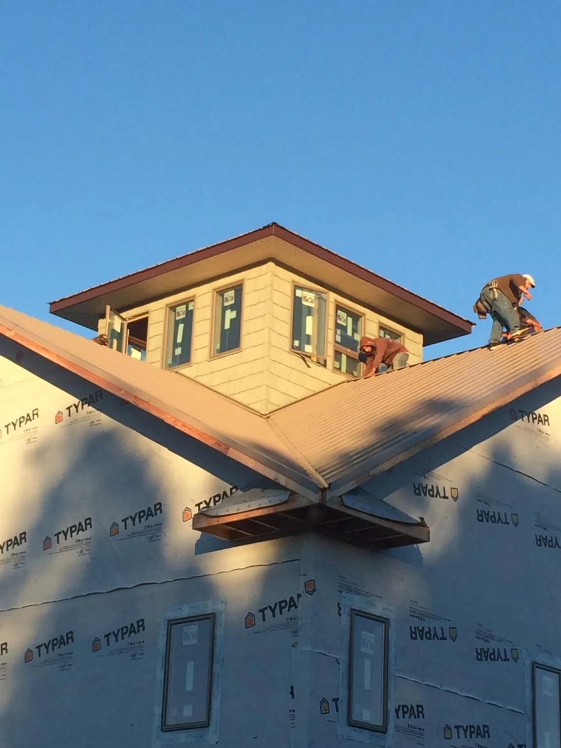 Roofers working around a rooftop cupola on a new metal roof at sunset — Roof Waterproofing in Weehawken by Roofing Brothers